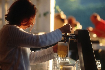 Eine junge Frau zapft ein Bier