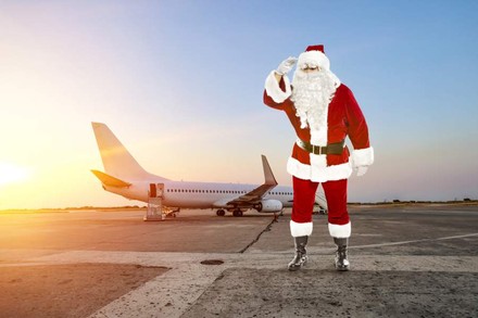 Ein Weihnachtsmann steht vor einem Flugzeug an einem Flughafen