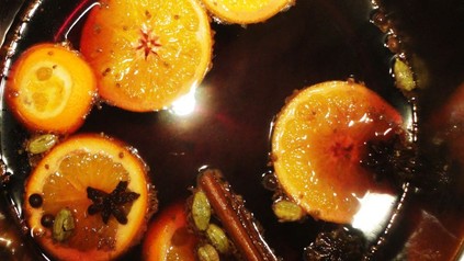 Ein Topf mit Glühwein, in dem Anis, Orangen und Zimtstangen schwimmen