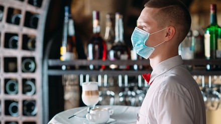 Ein Kellner mit Mundschutz