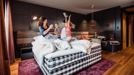 Mutter tollt mit Kindern in Hotelbett herum