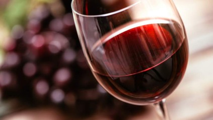 Ein Glas Wein vor einigen roten Weintrauben