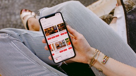 Junge Frau sitzt auf einer Bank und tippt in ihr Smartphone