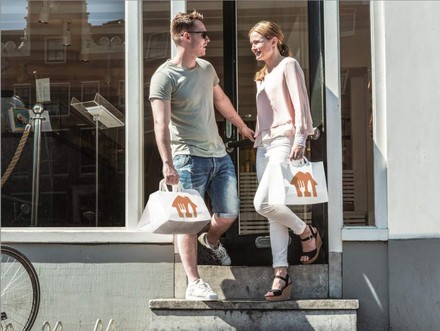 Zwei Personen verlassen ein Gebäude mit Lieferandotüten in den Händen