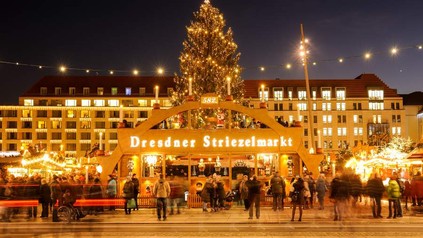 Der Eingang zum Dresdner Striezelmarkt bei Nacht mit vielen Besuchern