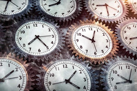 Mehrere Zahnräder auf denen Uhren abgebildet sind greifen ineinander