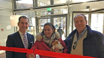 Eine Frau durchtrennt mit zwei Herren das rote Band im Steigenberger Hotel München