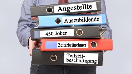 Mann hält Ordner mit der Aufschrift "Angestellte", "Auszubildende", "450 Euro Jober" und "Teilzzeitbeschäftigte"