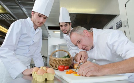 Ein Koch bringt seinen Auszubildenden etwas bei