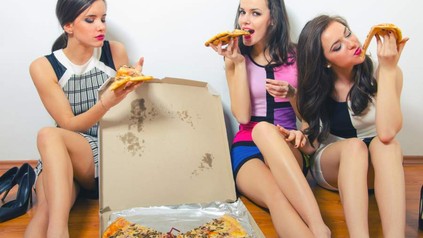drei Frauen sitzen um einen Pizzakarton herum und essen Pizza