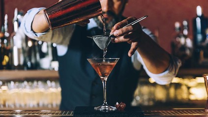 Barkeeper füllt den Cocktail von Mixer in ein Glas