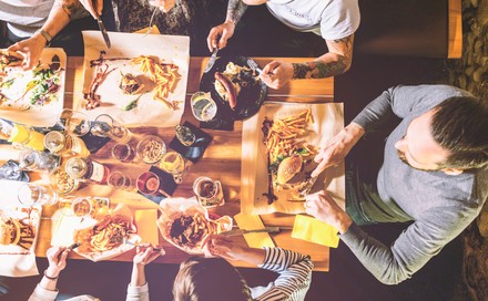 Personen an Esstisch mit Fastfood