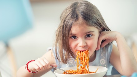 Ein Kind verputzt einen Teller Spaghetti.