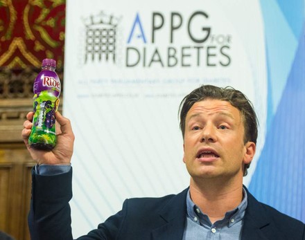 Jamie Oliver hält ein zuckerhaltiges Getränk in der Hand
