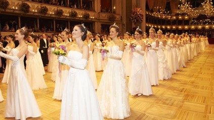 Viele junge Frauen in weißen Kleidern stehen in Reih und Glied in der wiener Staatsoper beim Opernball