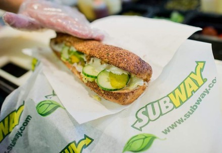 Ein frisches Subwaysandwich wird von einem Mitarbeiter eingepackt