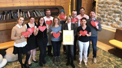 Karin Leeb, Martin Klein und die Mitarbeiter des Hochschober-Teams halten Herzen und die Urkunde von HolidayCheck in den Händen