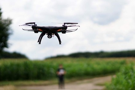 Eine Drohne in der Luft über grünen Feldern.