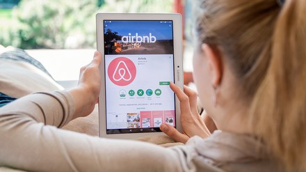 Junge Frau installiert die Airbnb-App auf einem Tablet
