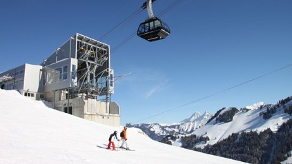Eine Seilbahn auf einem Berg und zwei Kinder beim Skifahren