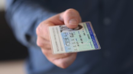 EIn Mann zeigt einen Ausweis vor