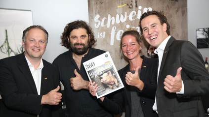 Konstantin Filippou und drei andere Würdenträger präsentieren ein Magazin auf dem Schwein ist fein steht