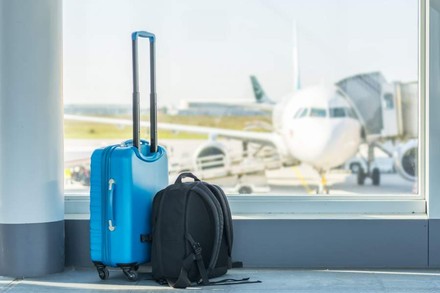 Ein Koffer und ein Rucksack stehen in einer Wartehalle am Flughafen
