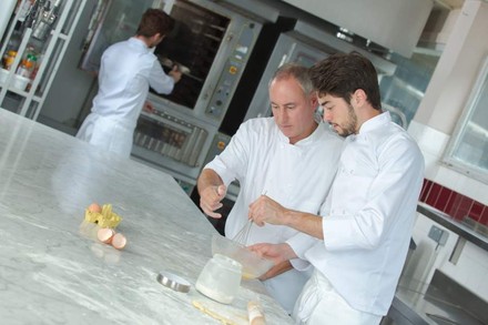 Ein Koch zeigt einem Azubi wie man richtig Eier aufschlägt