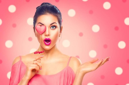 Frau hält sich ein künstliches Herz vor ihr rechtes Auge