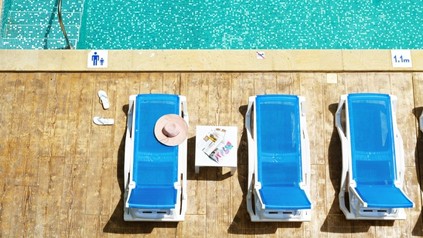 Ein Pool neben dem drei Strandliegen zu sehen sind