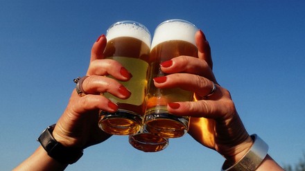 Hände halten drei Bier gegen den blauen Himmel