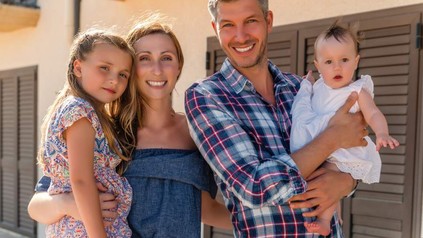 Eine Familie steht lächelnd vor einem Hotel