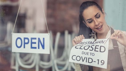 Frau hängt Corona-Schild an Restauranttüre ab