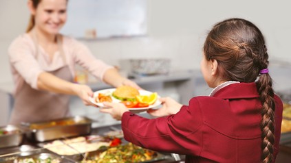 Ein Schulkind holt sich Essen in der Kantine