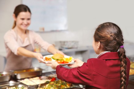 Ein Schulkind holt sich Essen in der Kantine
