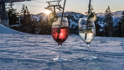 Zwei Modegetränke stehen im Schnee vor einem Skilift