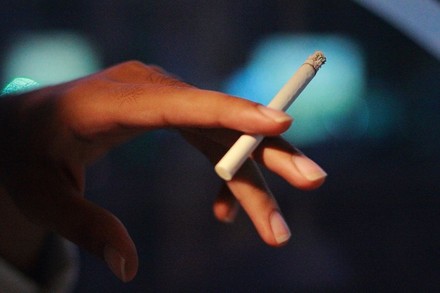 Eine Hand hält eine brennende Zigarette