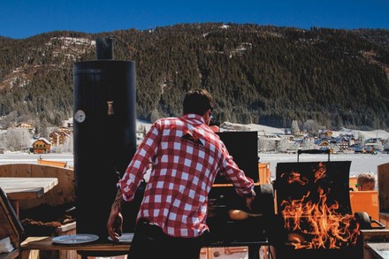 Ein Mann am Grill in einer verschneiten Landschaft am Kärntner Weissensee