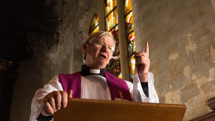 Ein Priester predigt vorwurfsvoll in einer Kirche