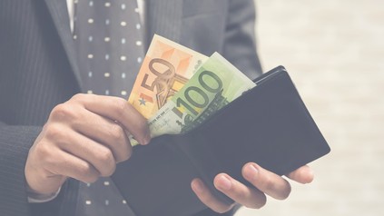 Mann zückt einen 50 Euro und 100 Euro Schein aus seiner Brieftasche