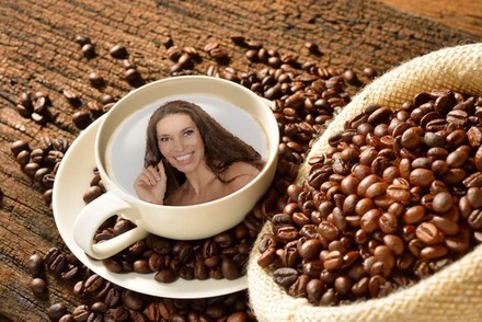 Neben einem Sack Kaffeebohnen steht eine Tasse Kaffe auf deren Oberfläche das Gesicht einer Frau zu sehen ist