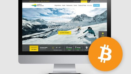 Ein Bildschirm auf dem eine Werbeseite von St. Moritz geöffnet ist, daneben ist das Logo von Bitcoin abgebildet