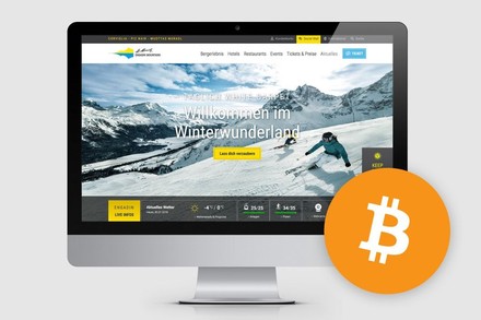 Ein Bildschirm auf dem eine Werbeseite von St. Moritz geöffnet ist, daneben ist das Logo von Bitcoin abgebildet