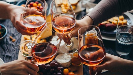 Menschen stoßen mit einem Glas Rosé an