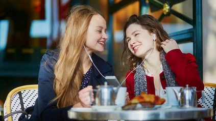 Zwei Frauen teilen sich einen Kopfhörer und hören Musik