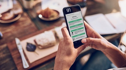 Person bezahlt eine Rechnung im Restaurant am Tisch mit dem Smartphone