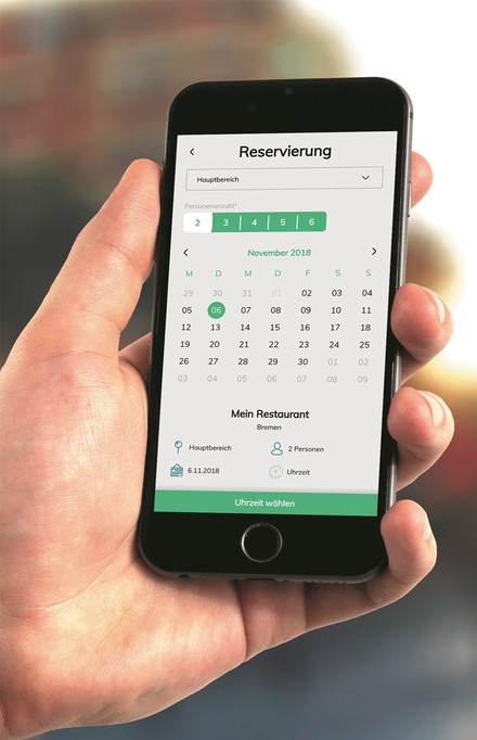 Hand hält Smartphone, auf dem ein Tischreservierungstool geöffnet ist