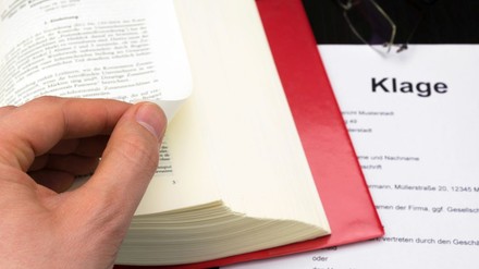 Klage mit Buch, Hand und Brille