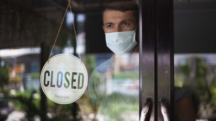 Gastronom hängt ein geschlossen-Schild auf
