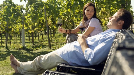 Mann und Frau genießen ein Glas Wein zwischen den Weinreben des Kamptales.